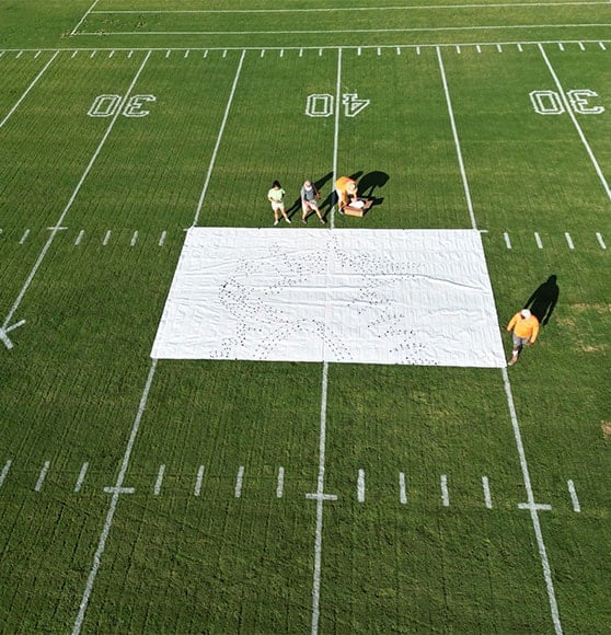 employees installing new event logo on football field