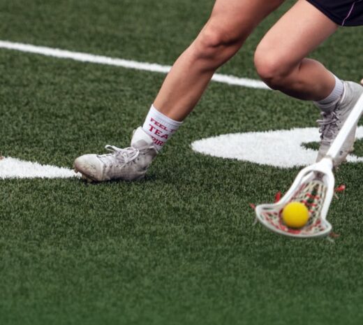 close-up of woman playing lacrosse on field with new line markings