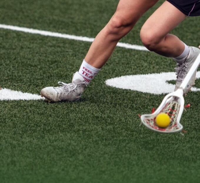 close-up of woman playing lacrosse on field with new line markings