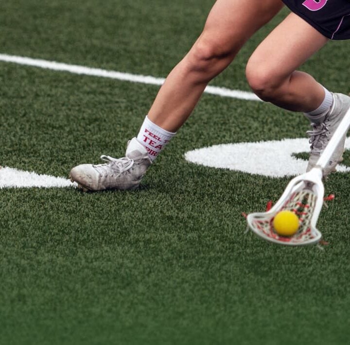 close-up of woman playing lacrosse on field with new line markings
